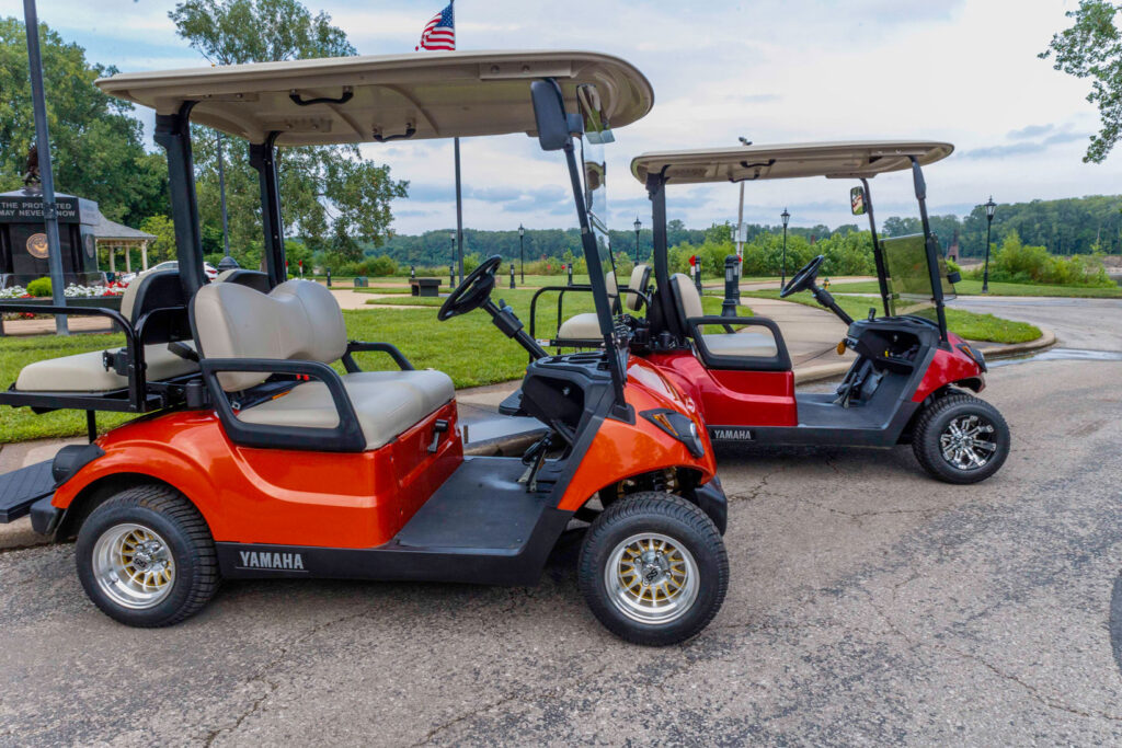 Orange and red golf carts for rent parked by the river near Historic St. Charles Main Street.